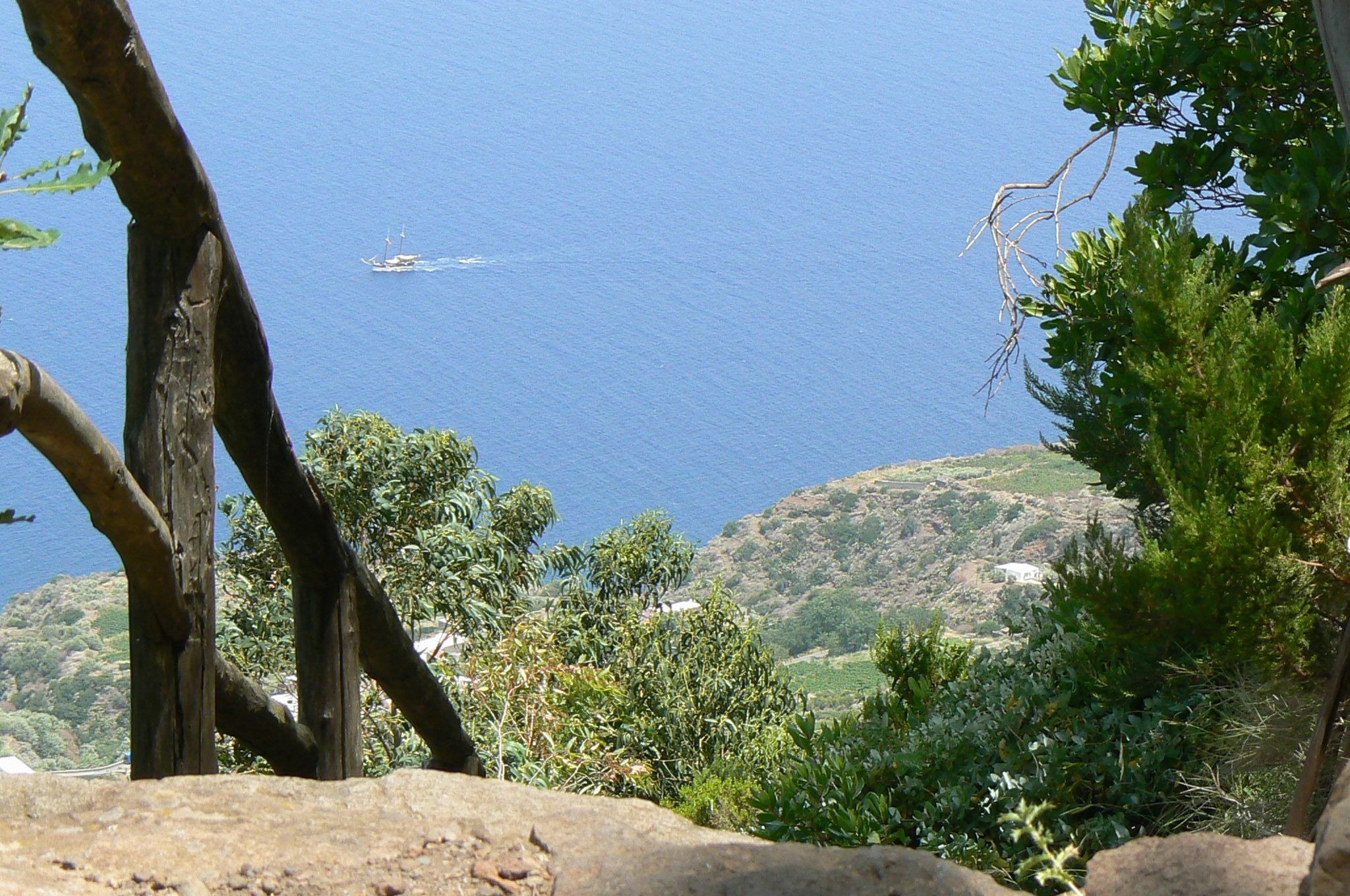 Un paisaje costero con vista al mar, un bote y vegetación circundante.