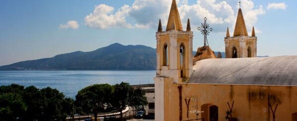 A coastal view with a church featuring two bell towers and a weather vane.
