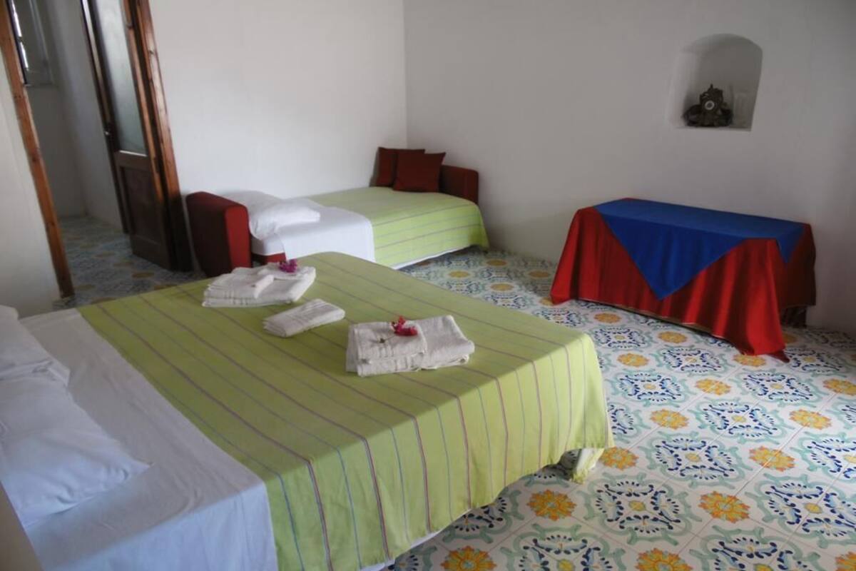 Een hotelkamer met twee bedden, een klein tafeltje met een rode tafelkleed en een vloer met een patroon.