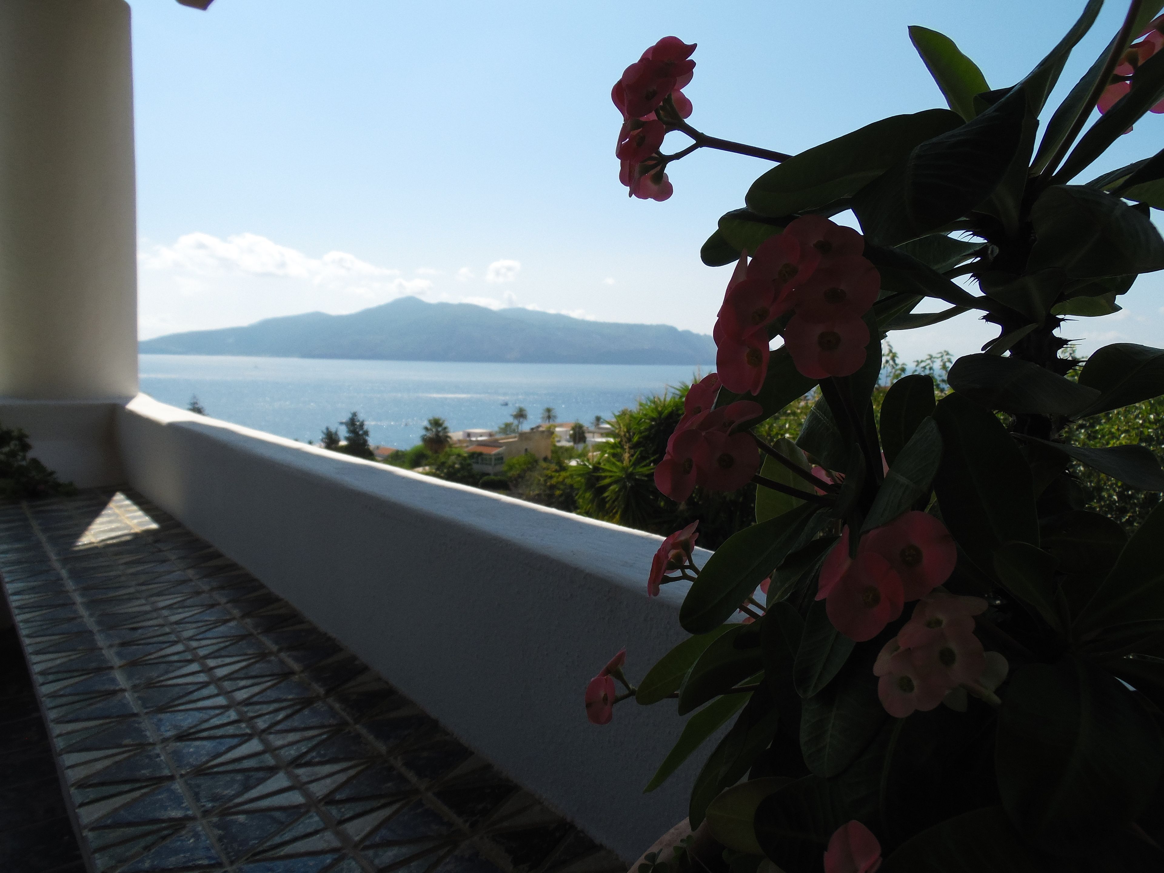 A balcony with a view of the sea and mountains.