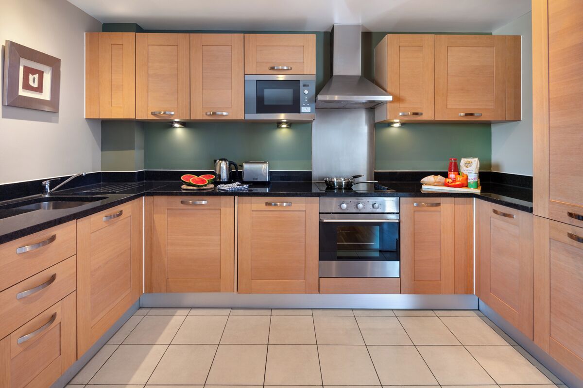 A modern kitchen with wooden cabinets, a microwave, an oven, and a sink.