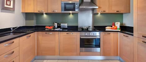 Eine moderne Küche mit Holzausstattung, einer Mikrowelle, einem Backofen und einem Spülbecken.