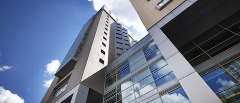A modern high-rise building with reflective glass windows and a clear blue sky.