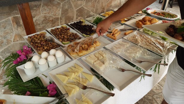 Un bufé con diversos alimentos, como aceitunas, huevos y panecillos.