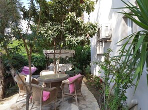 A patio with wicker furniture, a swing, and a garden area with plants and flowers. - Göcek Opera Hotel (Fethiye)