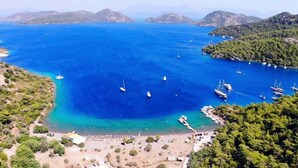 Una zona costera con aguas azul turquesa, embarcaciones y una playa con sombrillas.