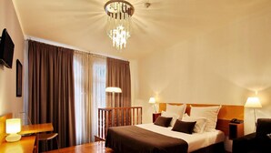 A hotel room with a bed, bedside tables, a desk, and a chandelier. - Hotel Mestre de Avis (Guimarães)