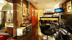 A modern bar area with a stone wall, bar stools, and a flat-screen TV mounted on the wall. - Hotel Mestre de Avis (Guimarães)