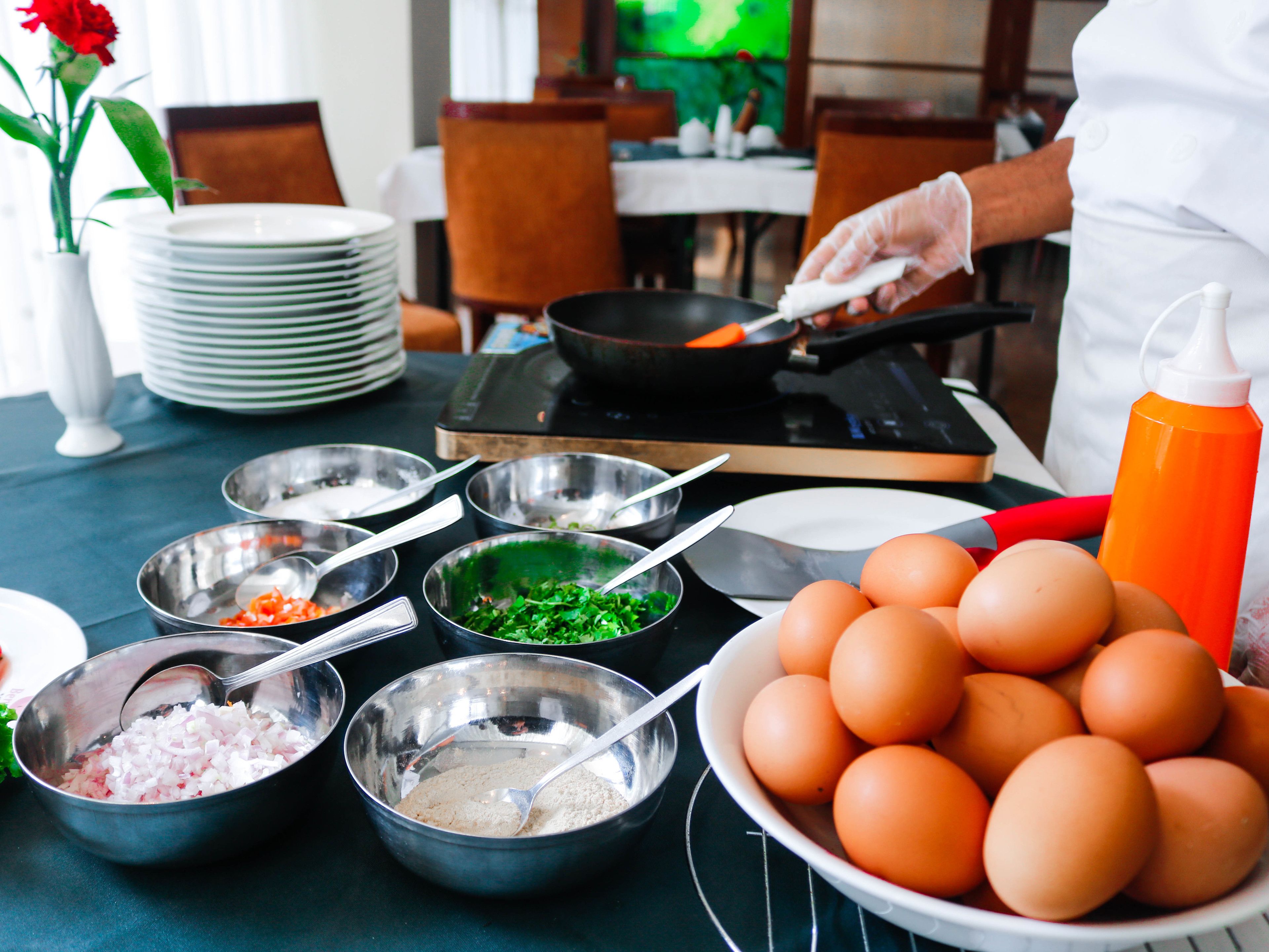 A kitchen area with various cooking utensils, ingredients, and a person wearing gloves preparing food.
