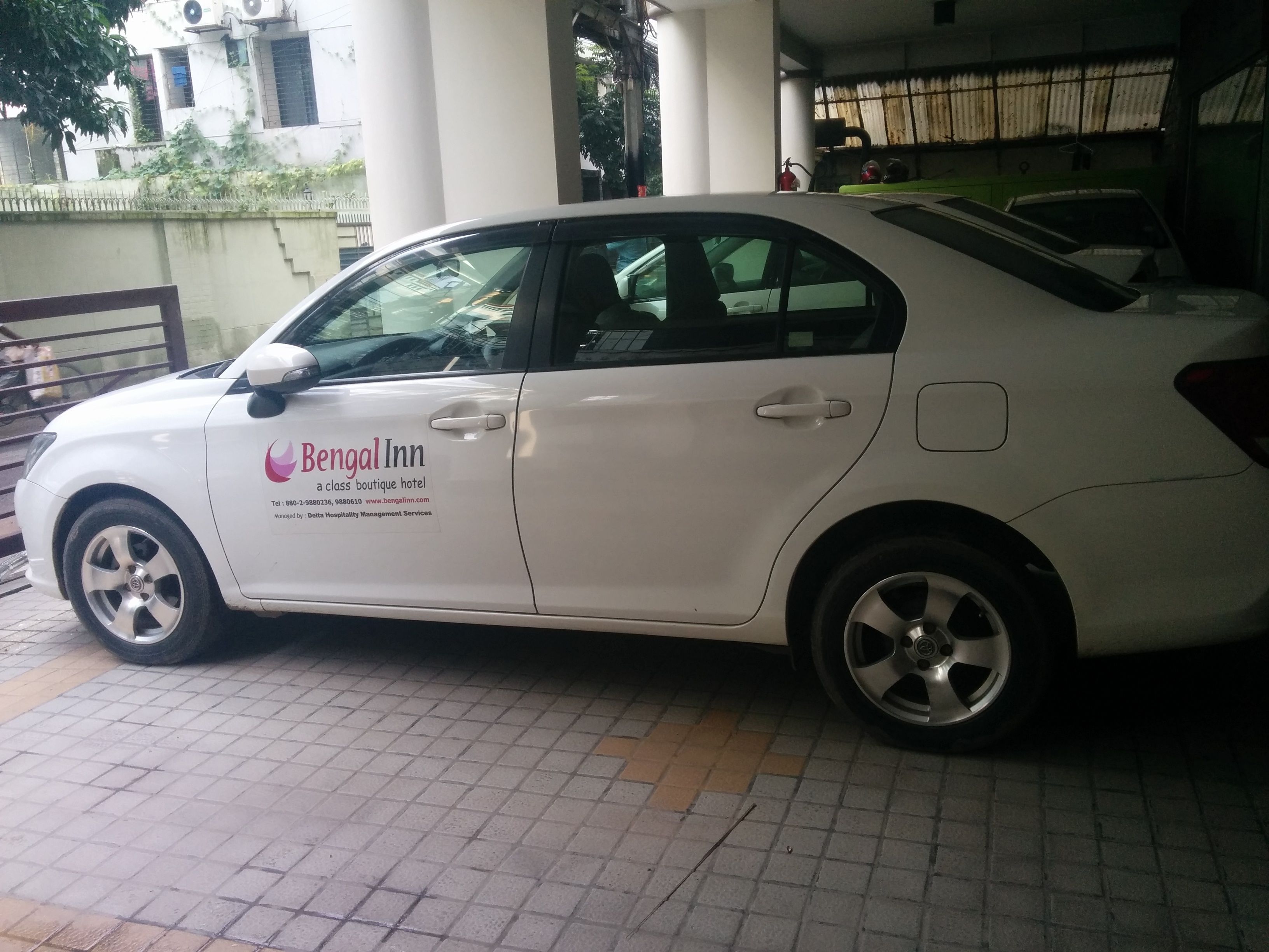 A white car parked in front of a building with a sign that reads "Bengal Inn."