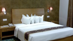 Habitación de hotel con una cama grande, dos mesitas de noche, un teléfono y dos lámparas de pared.