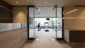 Un interior moderno con una puerta de cristal que da a un espacio para ejercicios con cintas de correr y bicicletas estáticas.