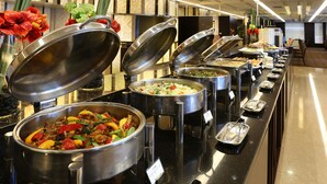 Un bufé con diversas opciones de comida, incluyendo una olla grande de chili y un tazón de ensalada.