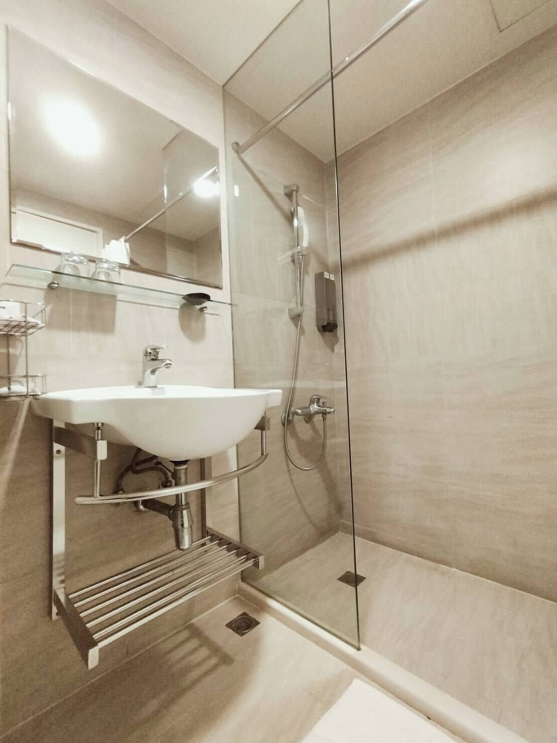 Un baño moderno con cabina de ducha de vidrio, un lavabo blanco y un espejo sobre el lavabo.
