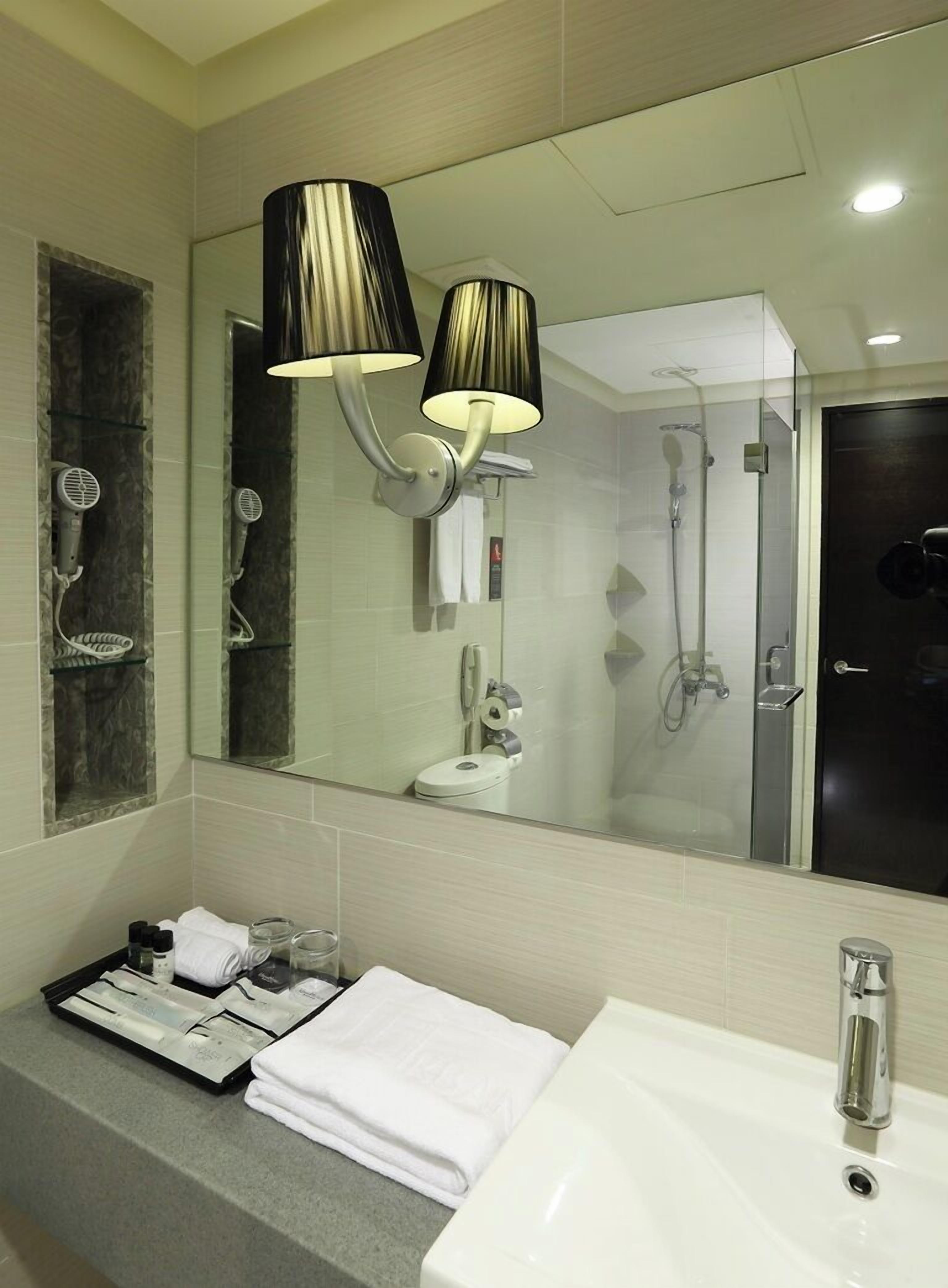 A modern bathroom with a large mirror, a sink, and a shower.