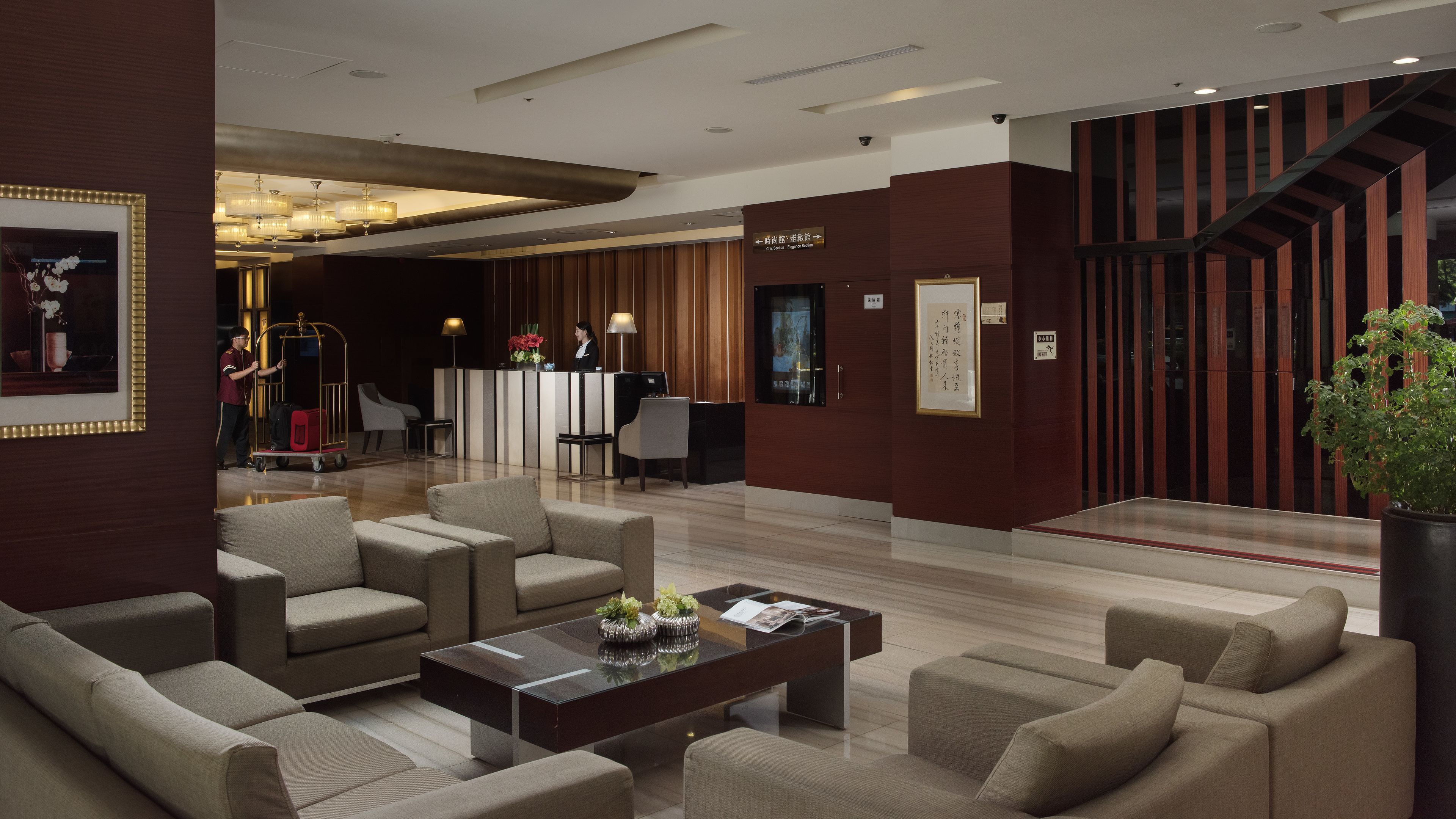 A modern lobby with a reception desk, seating area, and a staircase.