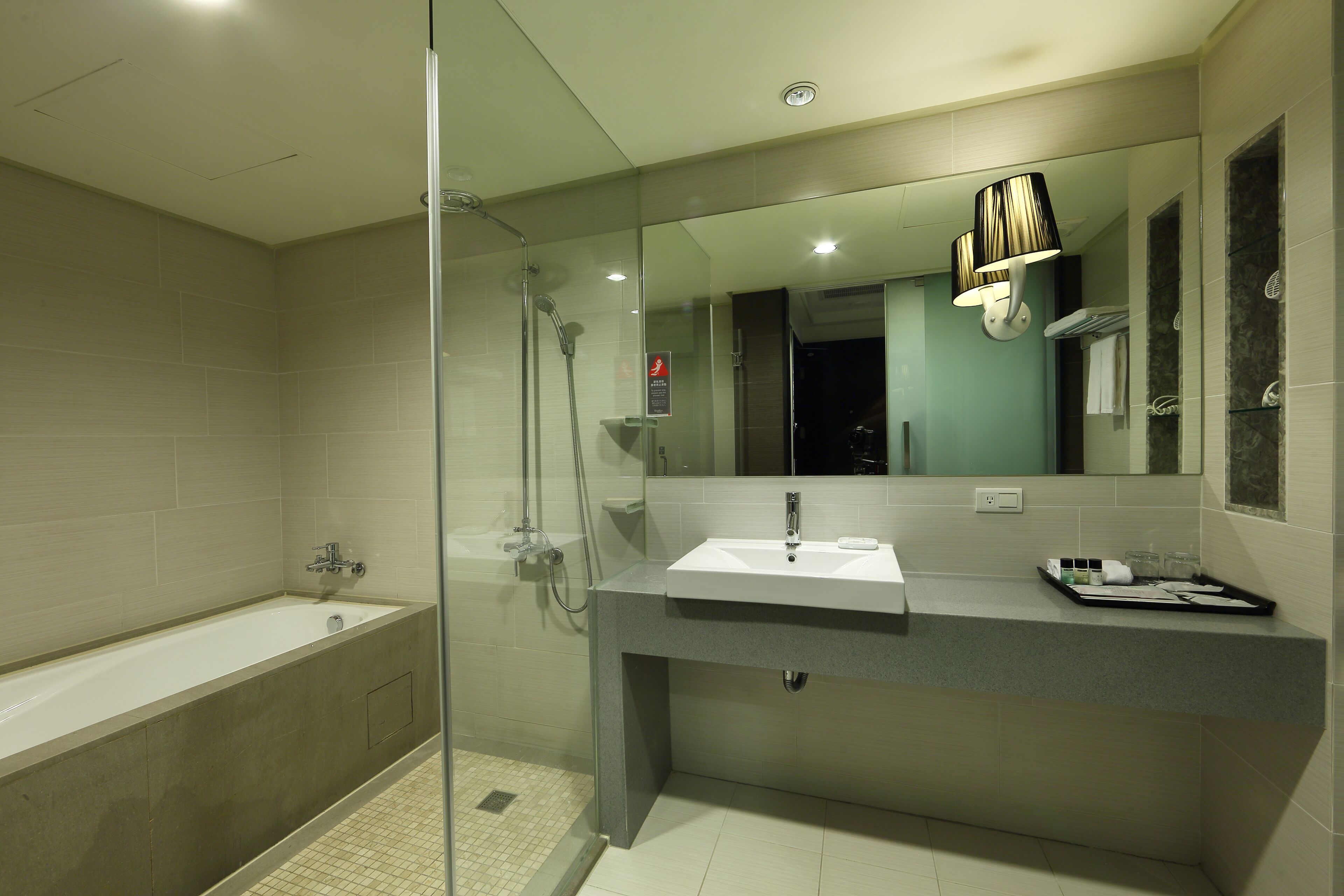 A modern bathroom with a glass-enclosed shower, a bathtub, and a vanity with a mirror.