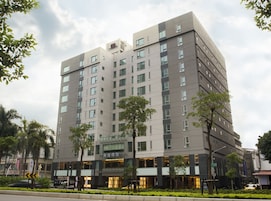 Un hotel a più piani dal design moderno, con un ingresso in evidenza caratterizzato da vetrate e un cartello pubblicitario.