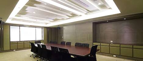 A conference room with a long table, chairs, and a large screen.