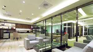 Una sala de estar moderna con un separador de vidrio, un comedor y una cocina visibles a través del separador.