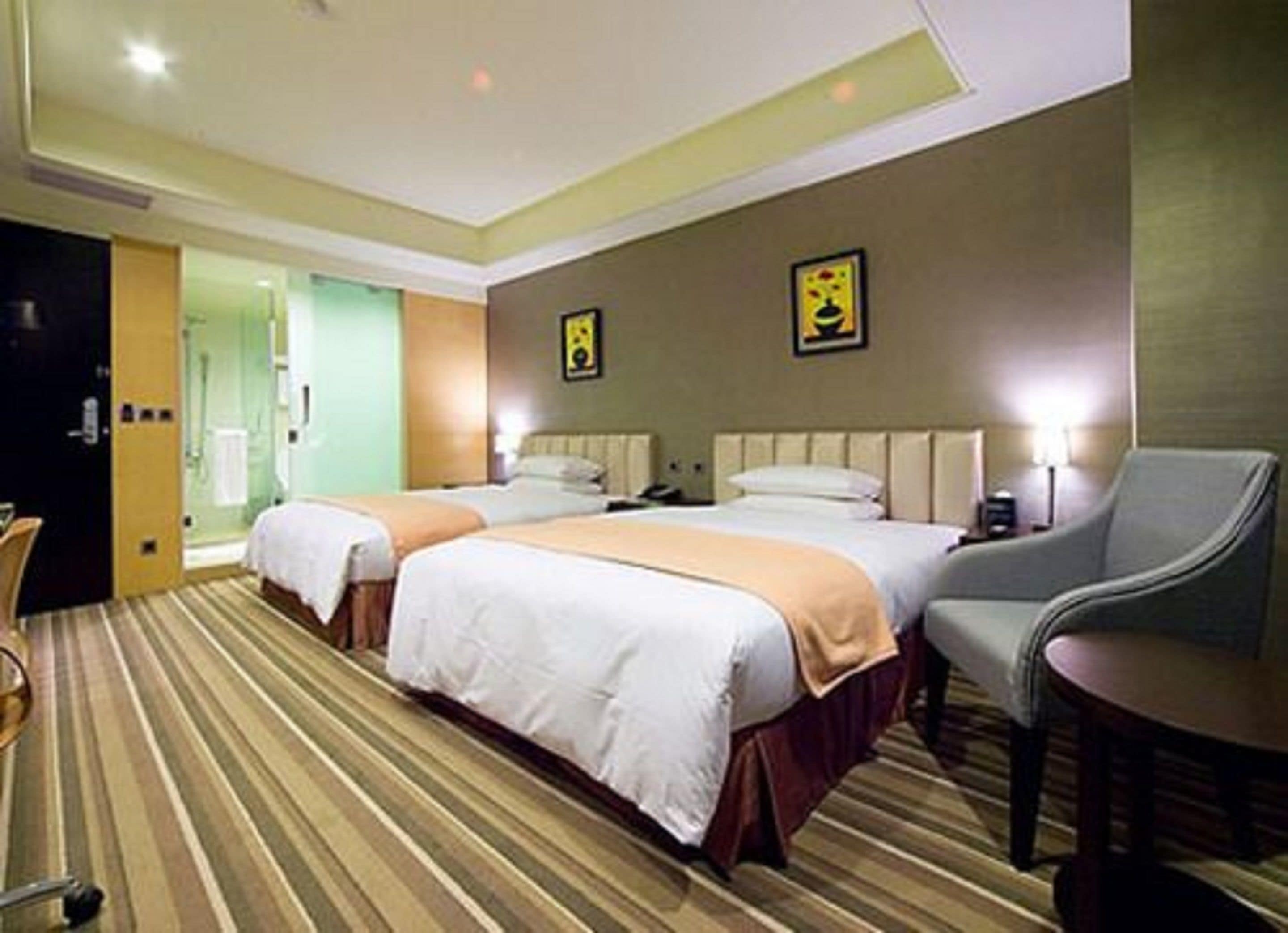 A hotel room with two beds, a chair, and a small table.
