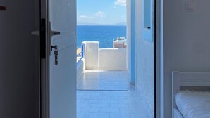 A room with a view of the sea, a bed, and a white door. - Blue Dolphin Aegina (Aegina)