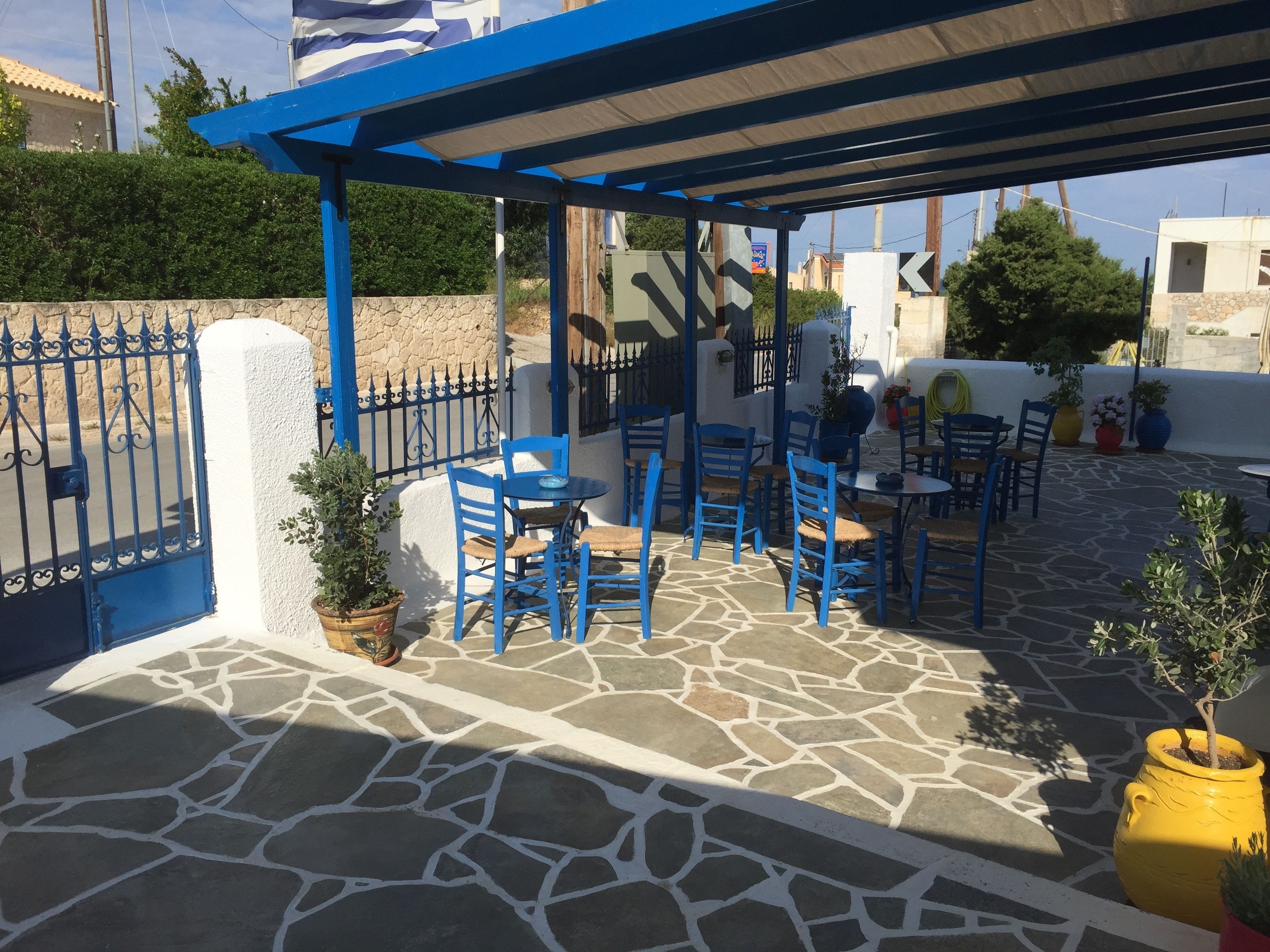 An outdoor patio with blue furniture and stone flooring.