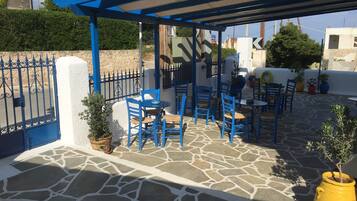 An outdoor patio with blue furniture and stone flooring.
