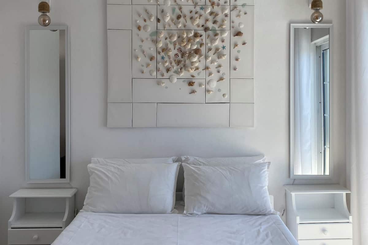 Een net opgemaakt bed met witte lakens en twee opgerolde handdoeken op een witte matras.