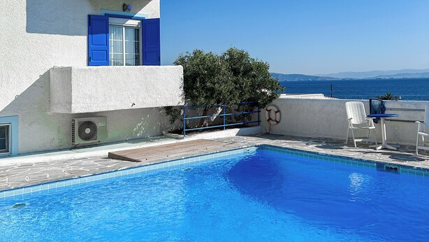A modern building with a pool, blue shutters, and a clear view of the sea. - Blue Dolphin Aegina (Aegina)
