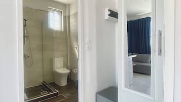 A modern bathroom with a glass-enclosed shower, a toilet, and a vanity with a mirror.