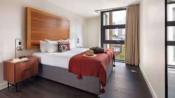 Une chambre d’hôtel moderne avec un grand lit, une table de chevet, une fenêtre avec des rideaux et une vue sur la ville.