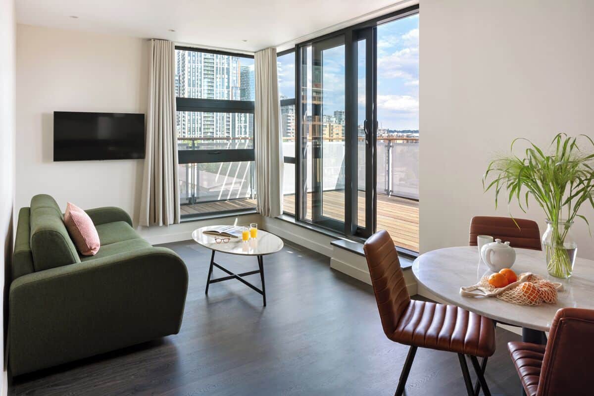 A modern living room with a green sofa, a coffee table, and a dining area with a table and chairs.