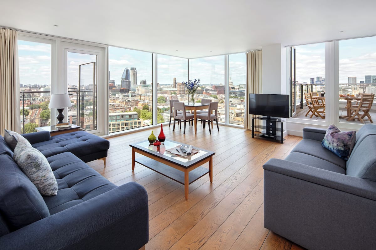 Ein modernes Wohnzimmer mit großem Stadtblick, einem Essbereich und einem Flachbildfernseher.