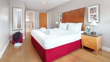 Una habitación de hotel con una cama grande, un cabecero de madera, una mesita de noche y un espejo.