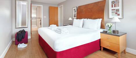 A hotel room with a large bed, a wooden headboard, a nightstand, and a mirror.