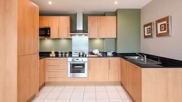 A modern kitchen with wooden cabinets, stainless steel appliances, and a black countertop.