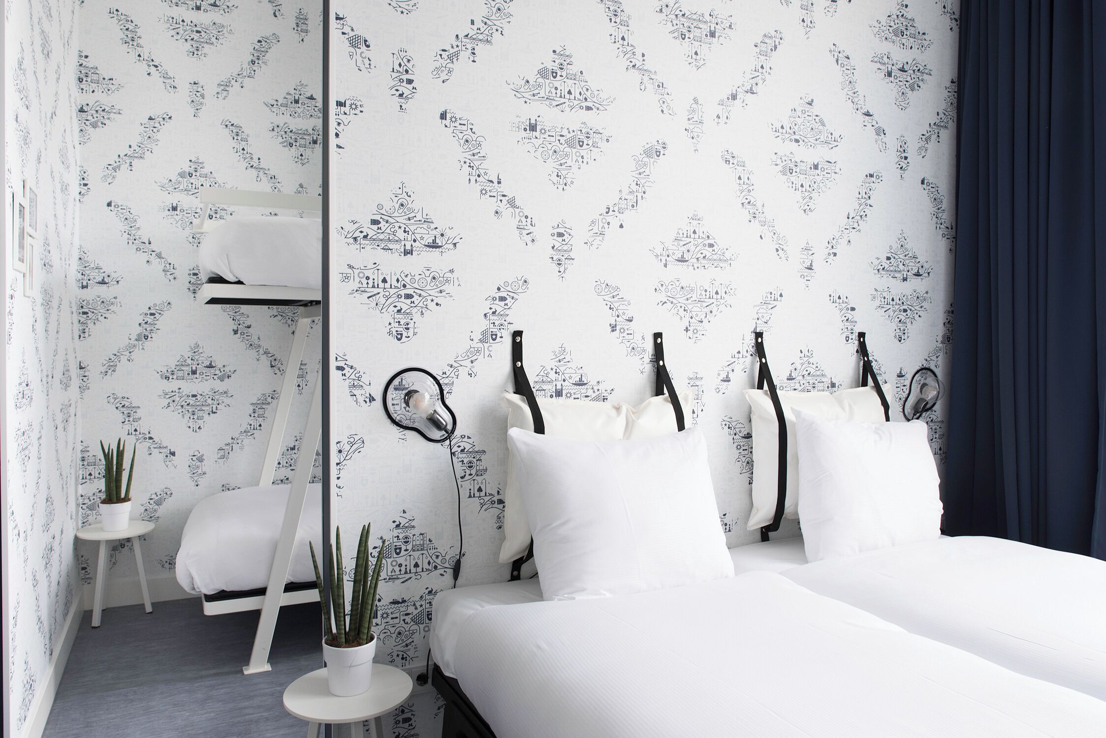 Un dormitorio con cama, mesitas de noche y un papel tapiz estampado.