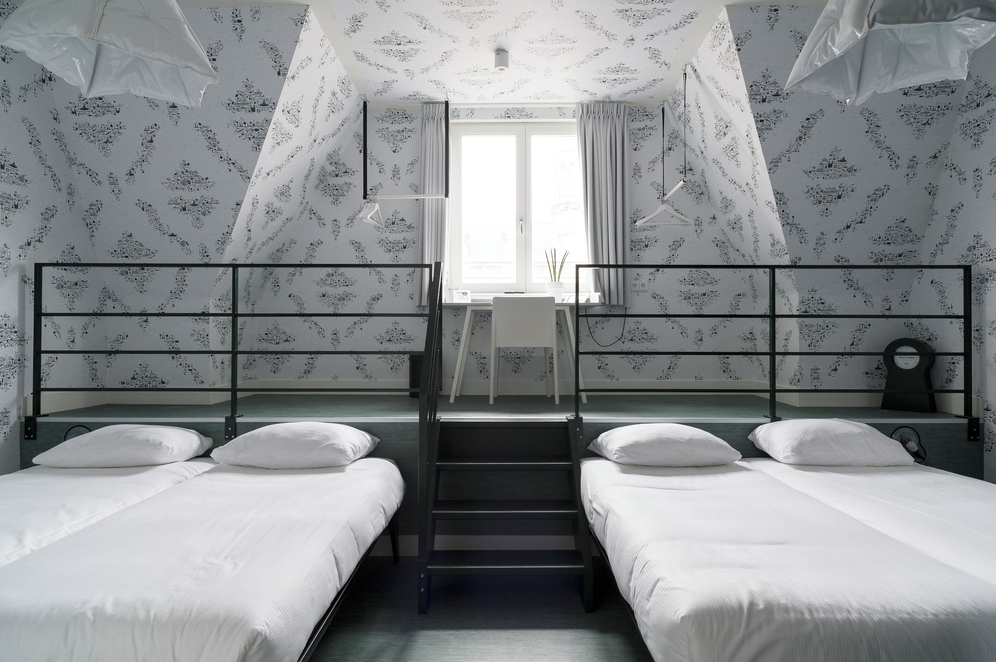 Une chambre de dortoir avec des lits superposés, un bureau et une fenêtre avec des rideaux.