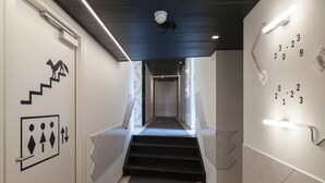 A modern hotel corridor with a staircase, a wall-mounted number sequence, and a handrail. - Kaboom Maastricht (Maastricht)