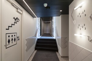 Un pasillo moderno de hotel con una escalera, una secuencia numérica en la pared y una barandilla.