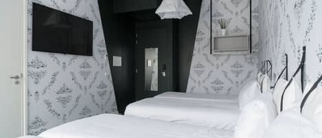 Una habitación de hotel moderna con una cama grande, un televisor de pantalla plana montado en la pared, una planta en maceta y una pared de acento negra y original.