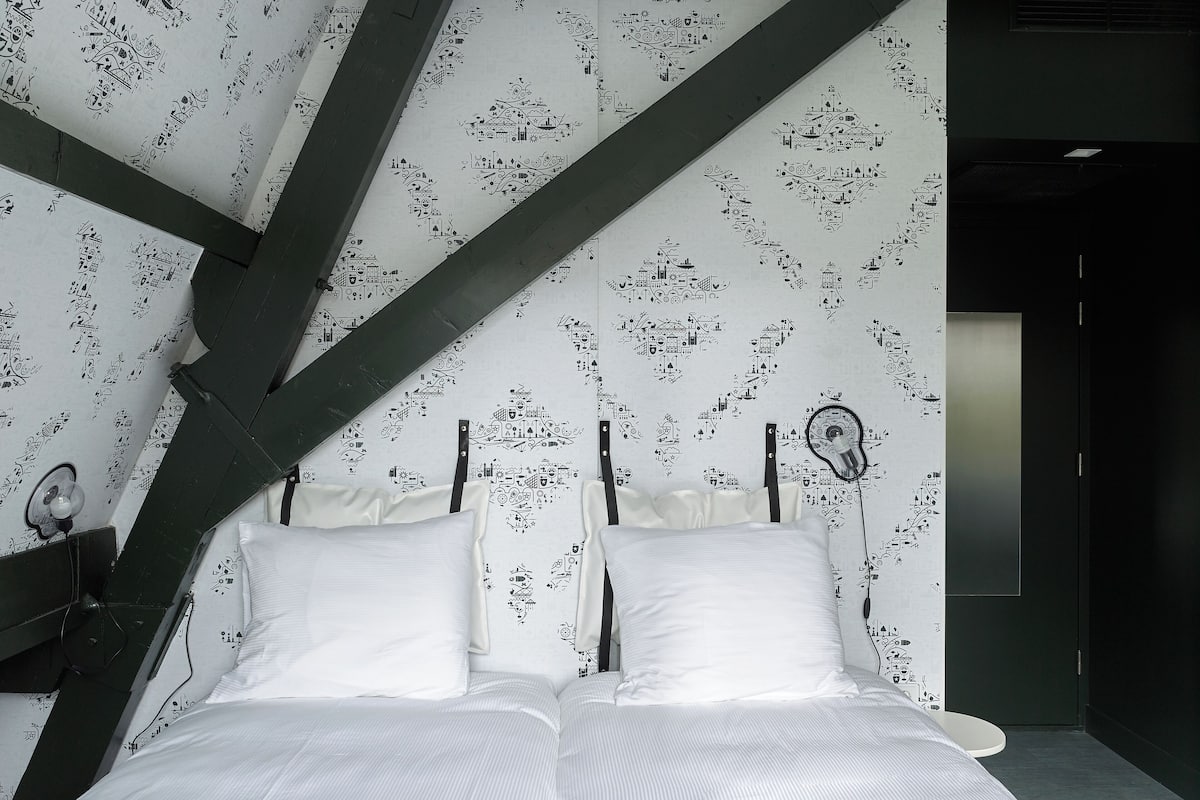 Ein modernes Schlafzimmer mit einem Bett, Kissen und einer Wand mit Schwarz-Weiß-Mustern.