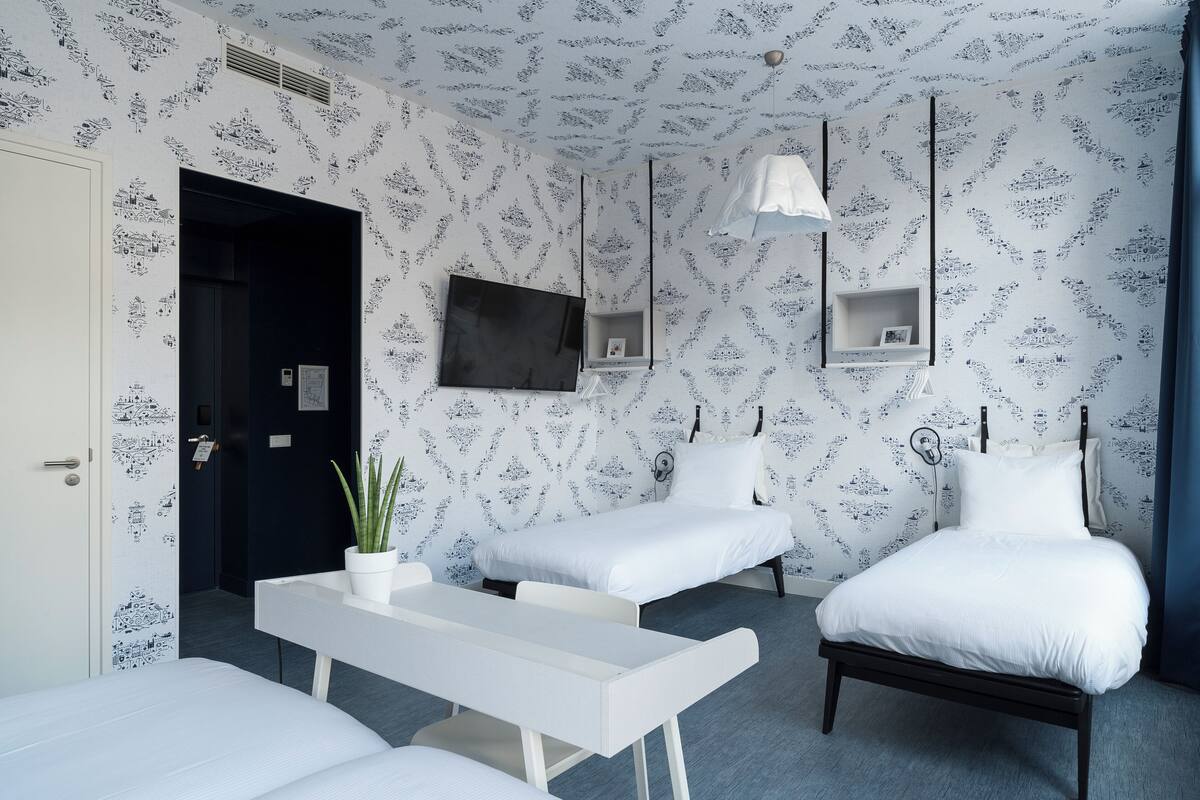 Ein modernes Hotelzimmer mit einem Bett, zwei Nachttischen, einem Fernseher und einer Pflanze.