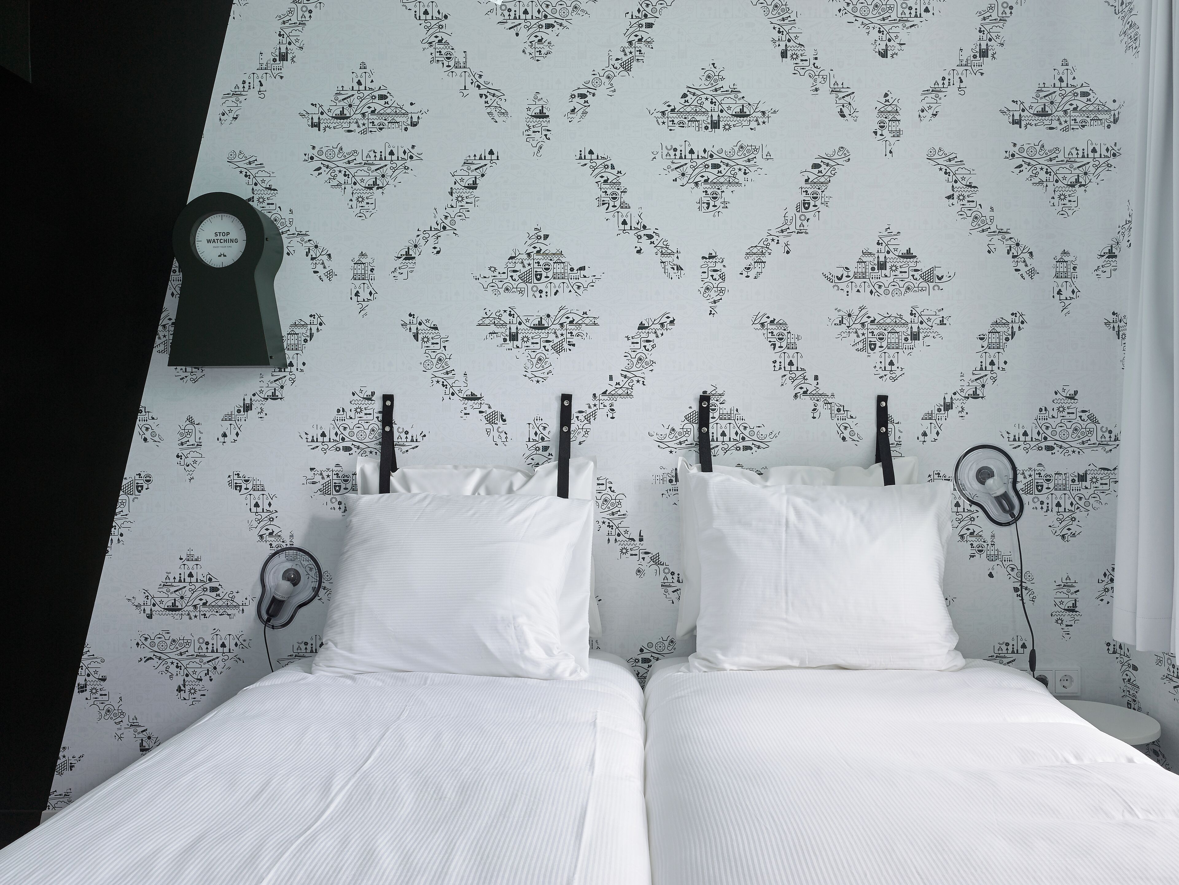Un dormitorio con dos camas, un reloj en la pared y un papel tapiz estampado.