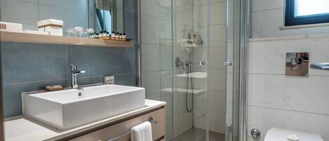 A modern bathroom with a glass-enclosed shower, a large sink, and a toilet.