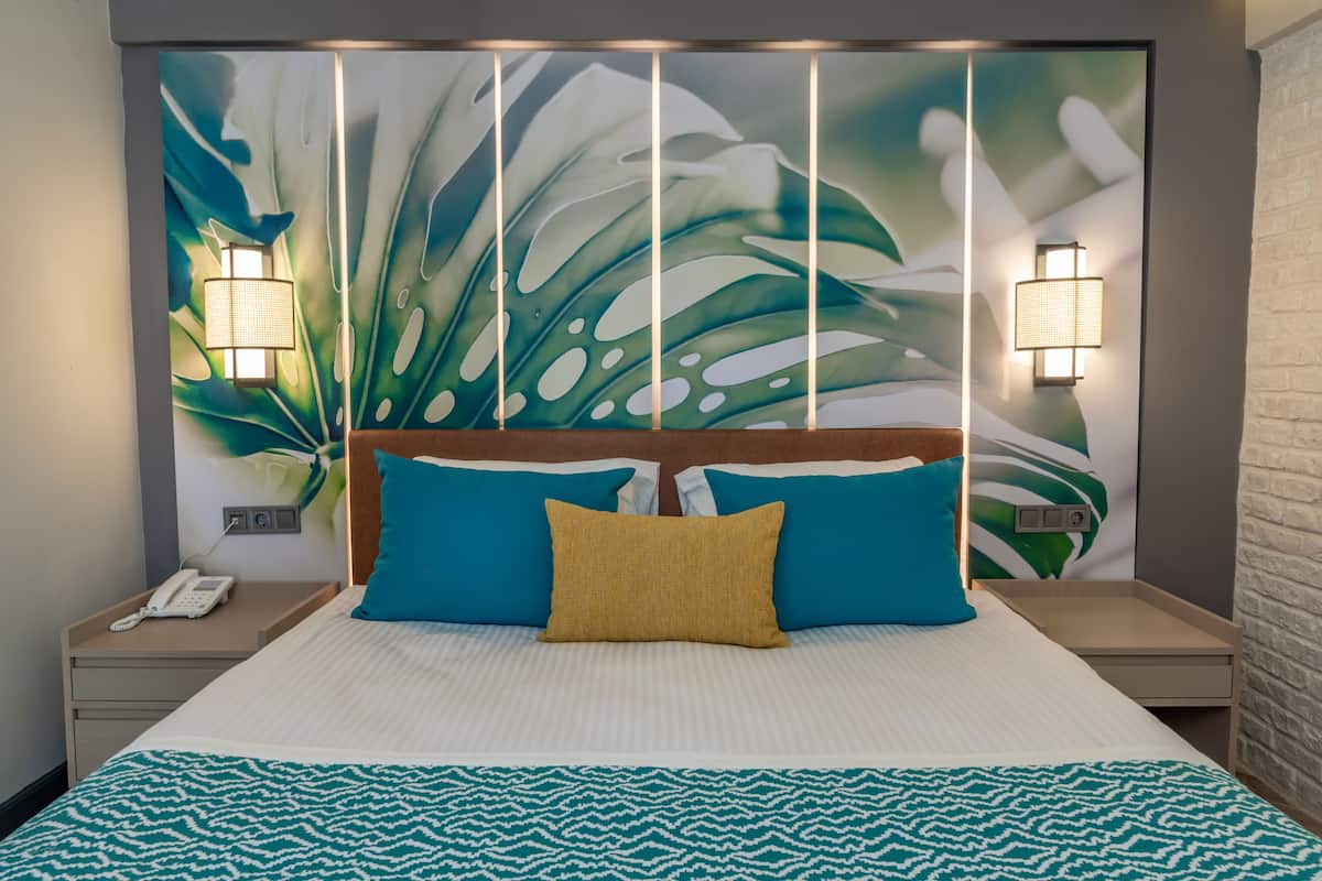 A hotel room with a large bed, two nightstands, a telephone, and wall-mounted lamps.