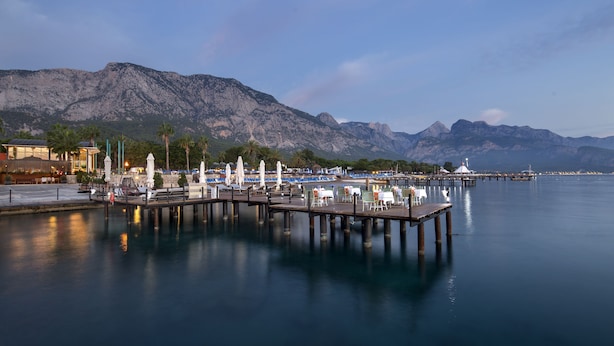 A waterfront pier with seating and a view of mountains. - Baia Salima Kemer (Kemer)
