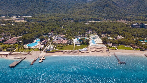 An aerial view of a coastal resort with multiple swimming pools, a beach area, and a pier extending into the sea. - Baia Salima Kemer (Kemer)