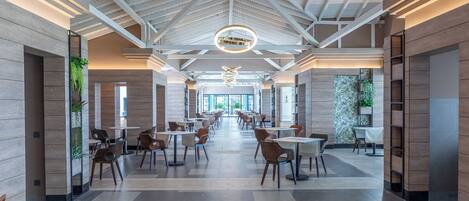 A spacious indoor area with high ceilings and a modern design, featuring multiple seating arrangements and a central decorative light fixture.